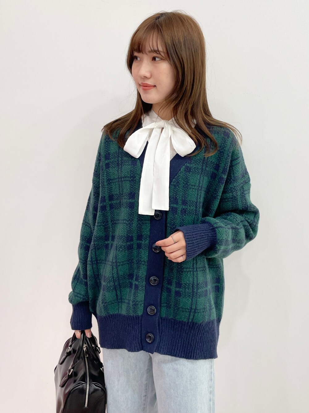 ブラック系のボストンバッグ、ベージュ系のブーツ、ブルー系のカーディガン/ボレロを着用したレディースの秋コーディネートの2枚目の写真