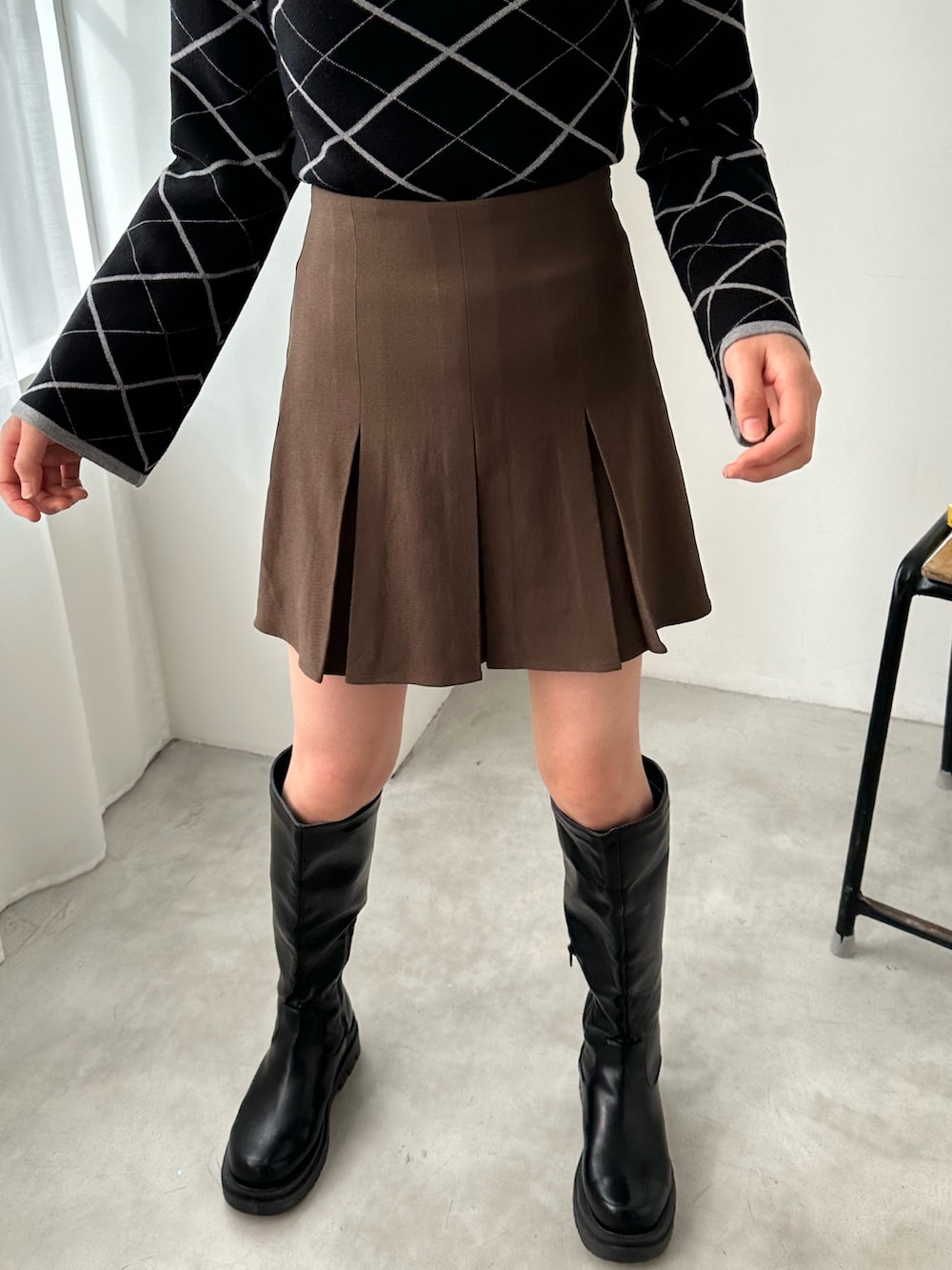 ブラウン系のスカート、ブラック系のニット/セーター、ブラック系のブーツを着用したレディースの冬コーディネートの4枚目の写真