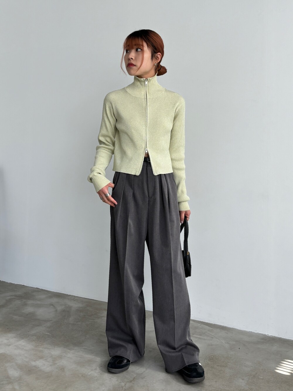 グレー系のスラックス、ブラック系のスニーカー、ベージュ系のニット/セーターを着用したレディースの冬コーディネートの3枚目の写真