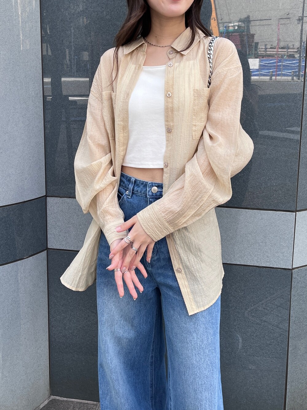 ブルー系のデニムパンツ、ベージュ系のシャツ/ブラウス、ホワイト系のキャミソールを着用したレディースの春コーディネートの2枚目の写真
