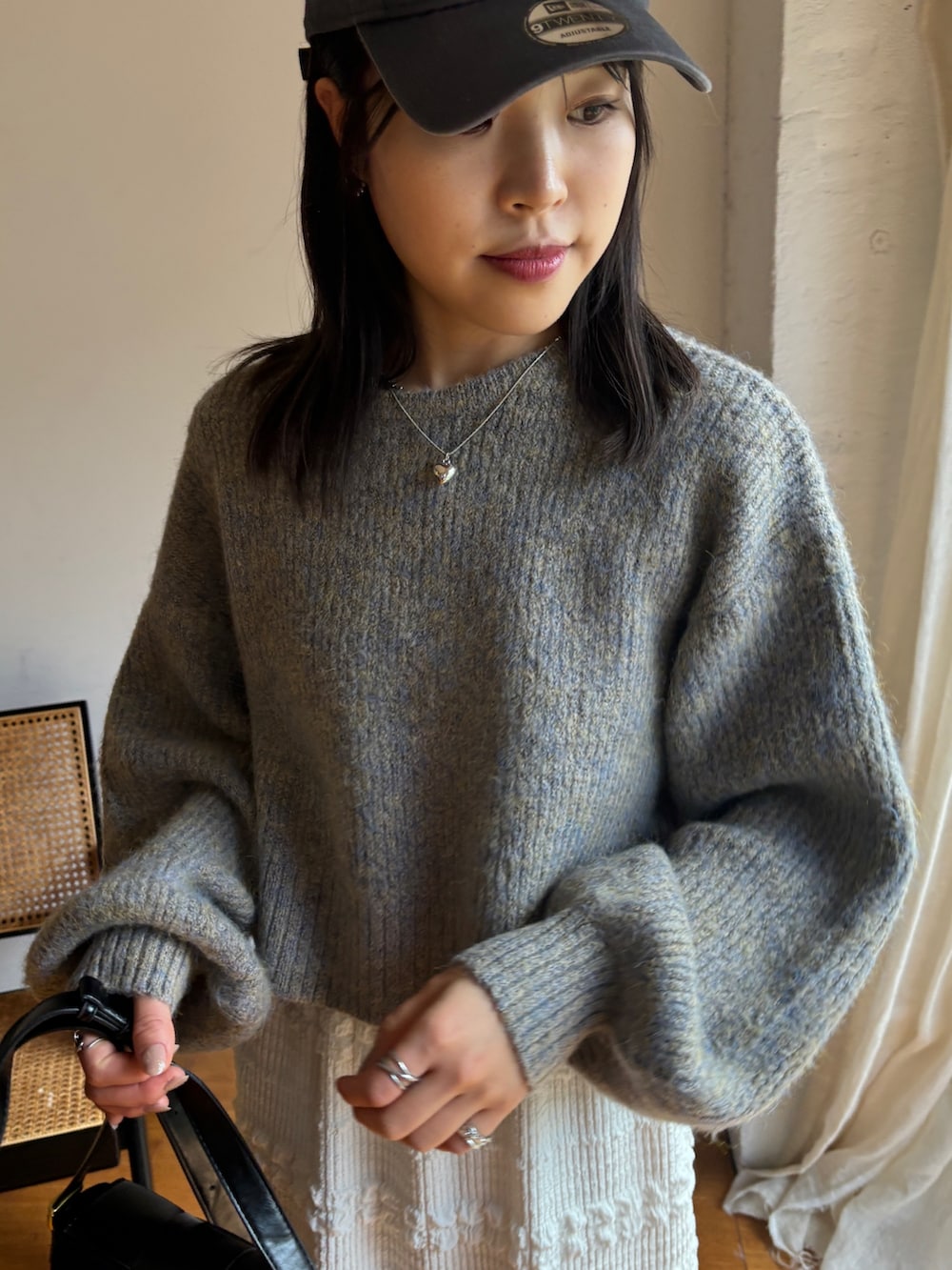 ベージュ系のニット/セーター、ホワイト系のスカート、ブラック系のスニーカーを着用したレディースの秋コーディネートの3枚目の写真