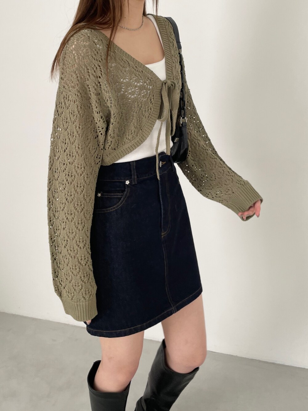 ブルー系のデニムスカート、グリーン系のカーディガン/ボレロ、ブラック系のブーツを着用したレディースの冬コーディネートの3枚目の写真