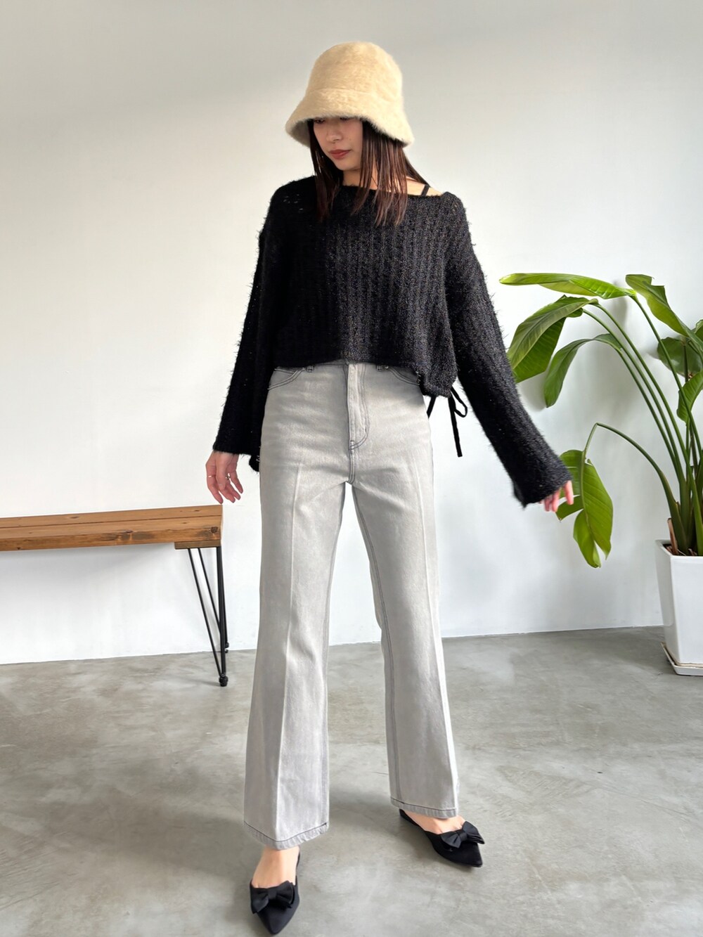 グレー系のデニムパンツ、ブラック系のニット/セーター、ベージュ系のハットを着用したレディースの冬コーディネートの3枚目の写真