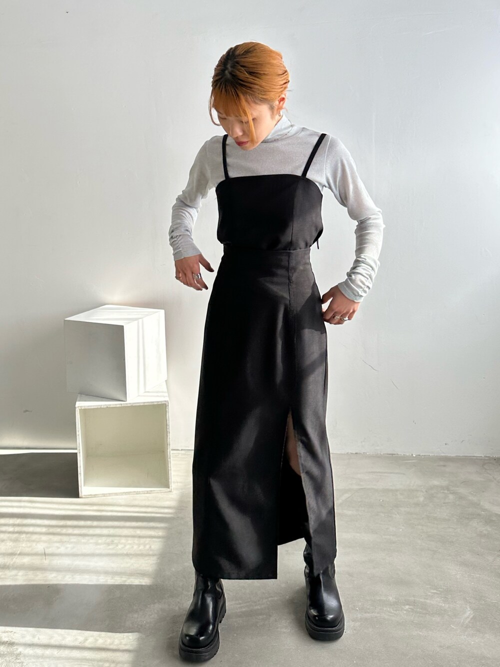 ブラック系のワンピース、ホワイト系のTシャツ/カットソー、ブラック系のブーツを着用したレディースの冬コーディネートの3枚目の写真