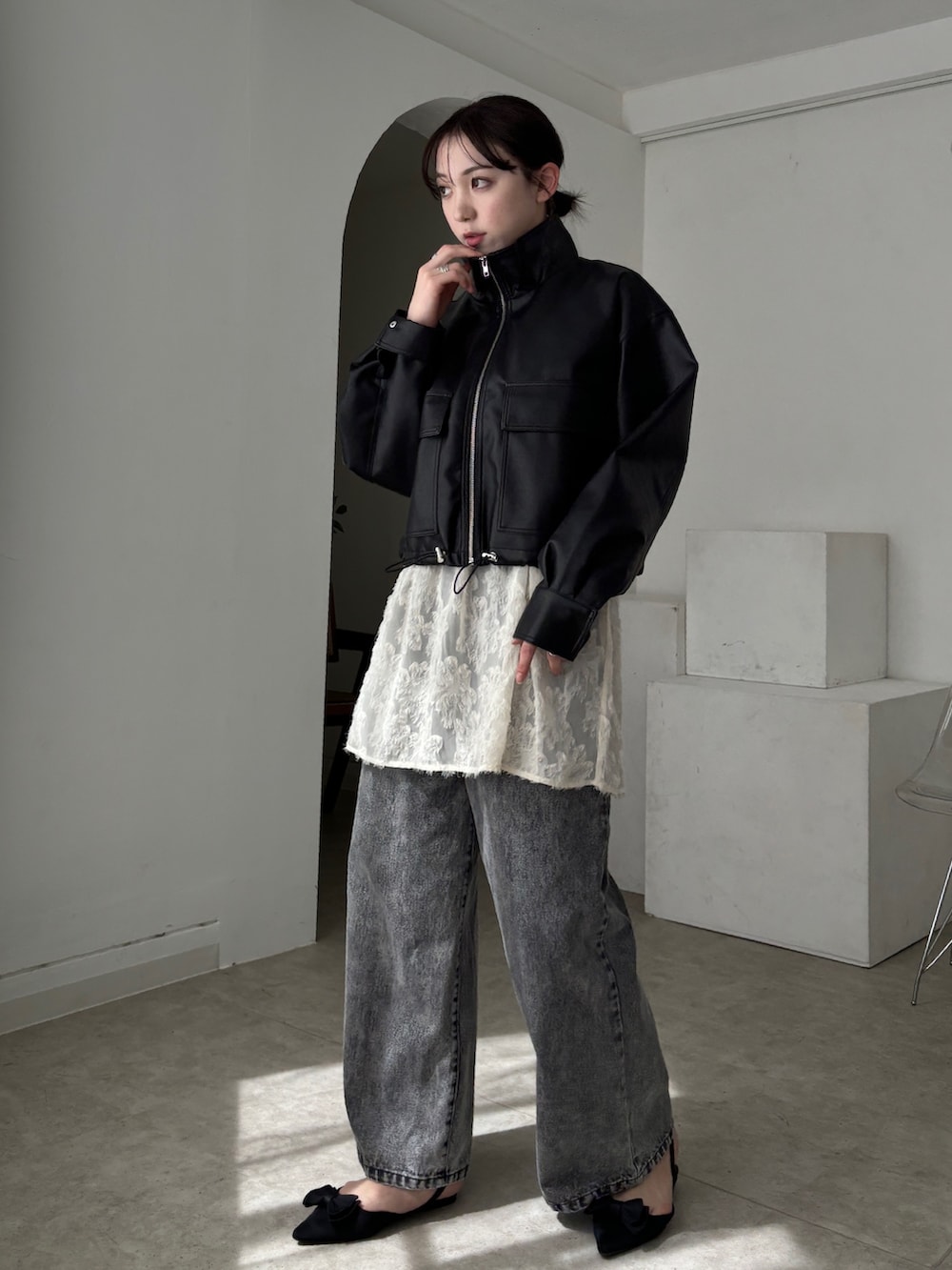 ホワイト系のチュニック、ブラック系のブルゾン、グレー系のデニムパンツを着用したレディースの春コーディネートの5枚目の写真