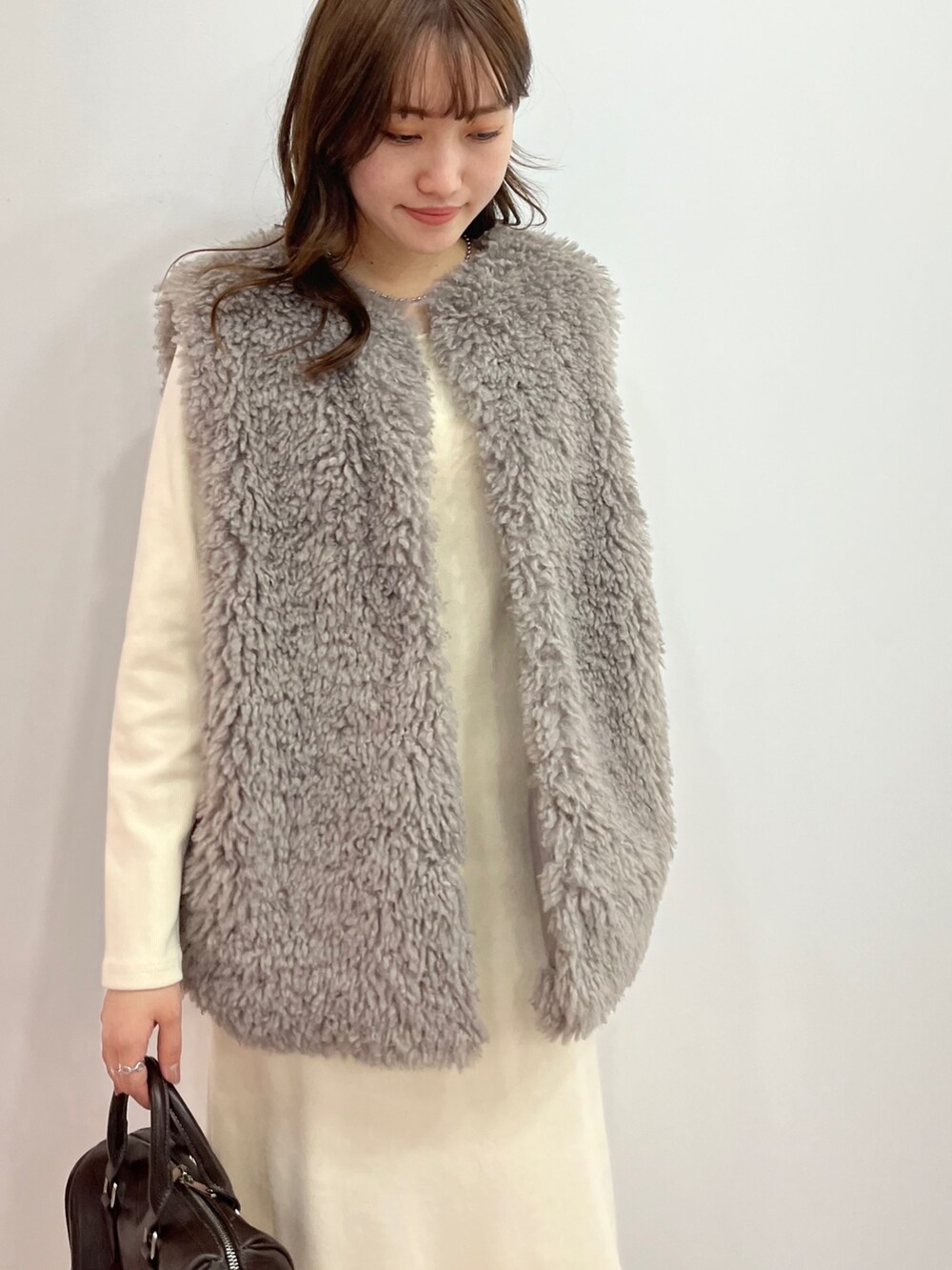 ホワイト系のワンピース、グレー系のベスト、ブラック系のボストンバッグを着用したレディースの秋コーディネートの3枚目の写真