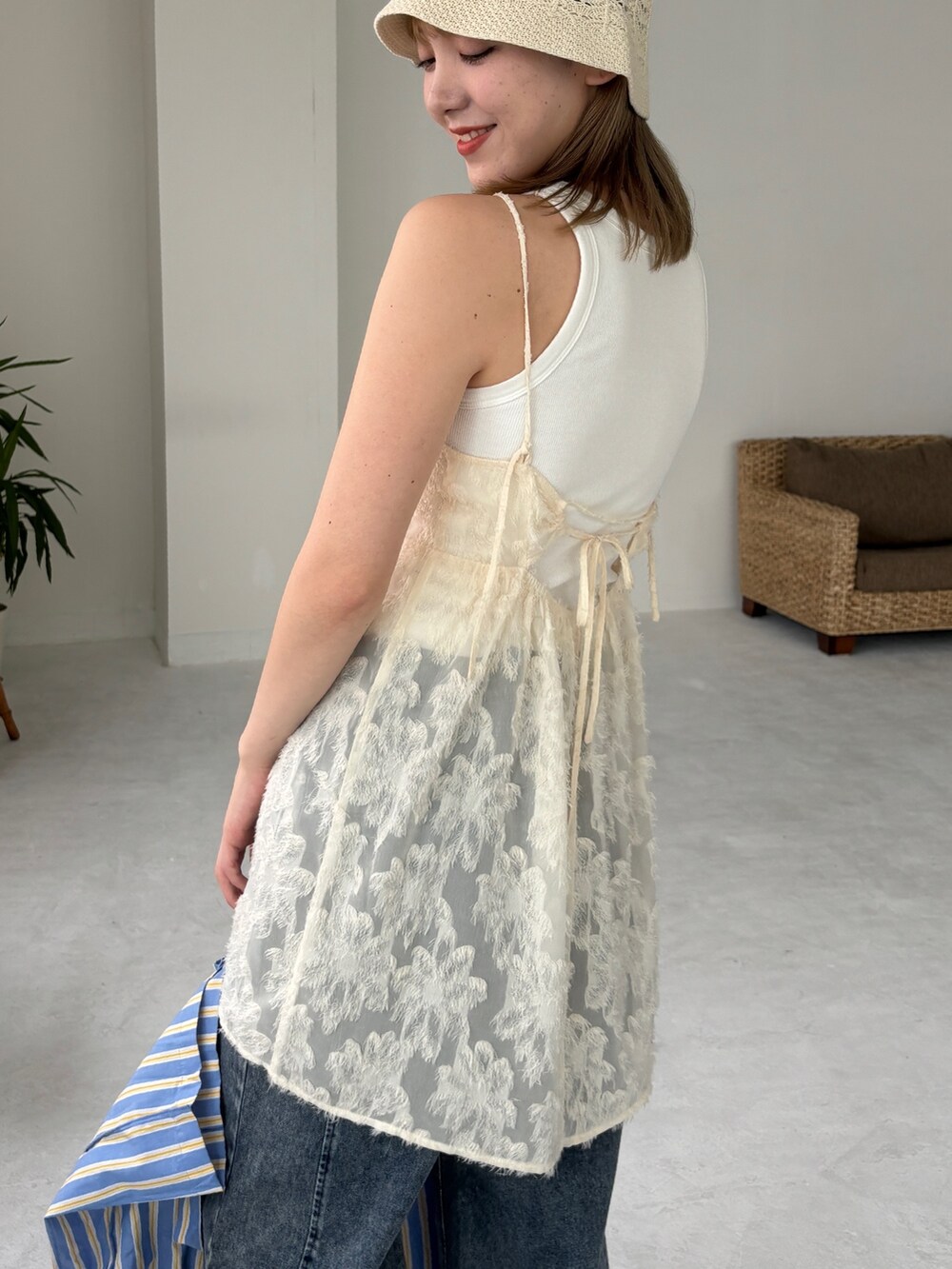 ブルー系のトートバッグ、ホワイト系のチュニック、ブルー系のデニムパンツを着用したレディースの夏コーディネートの6枚目の写真