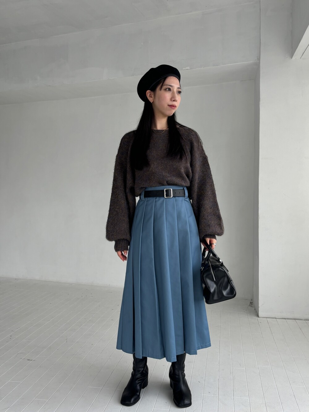 ブラウン系のニット/セーター、ブルー系のスカート、ブラック系のブーツを着用したレディースの秋コーディネートの4枚目の写真