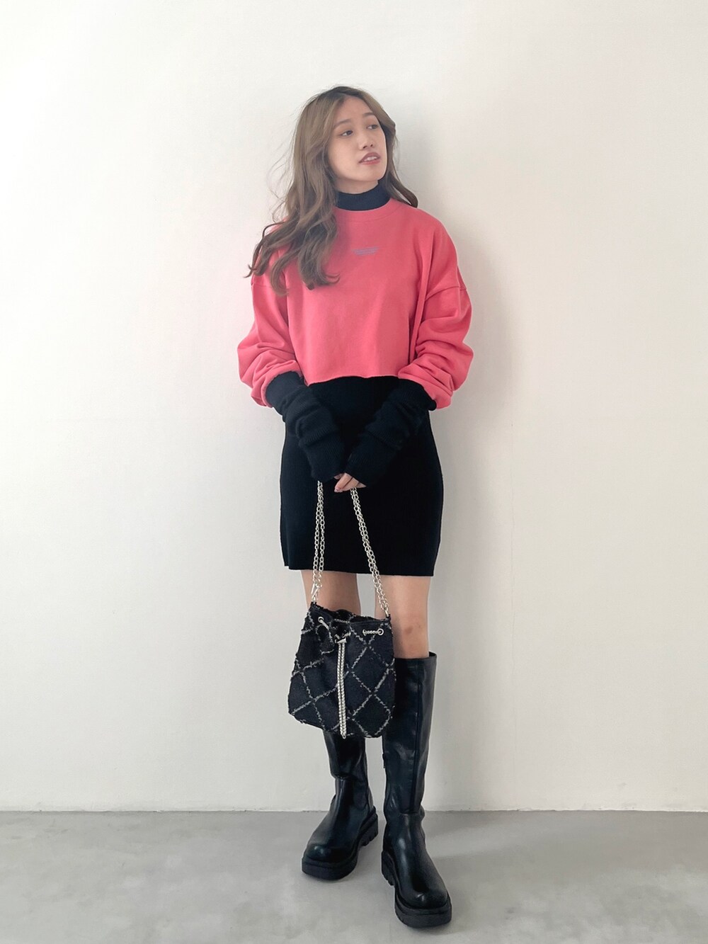 ブラック系のワンピース、ピンク系のスウェット、ブラック系のブーツを着用したレディースの秋コーディネートの3枚目の写真