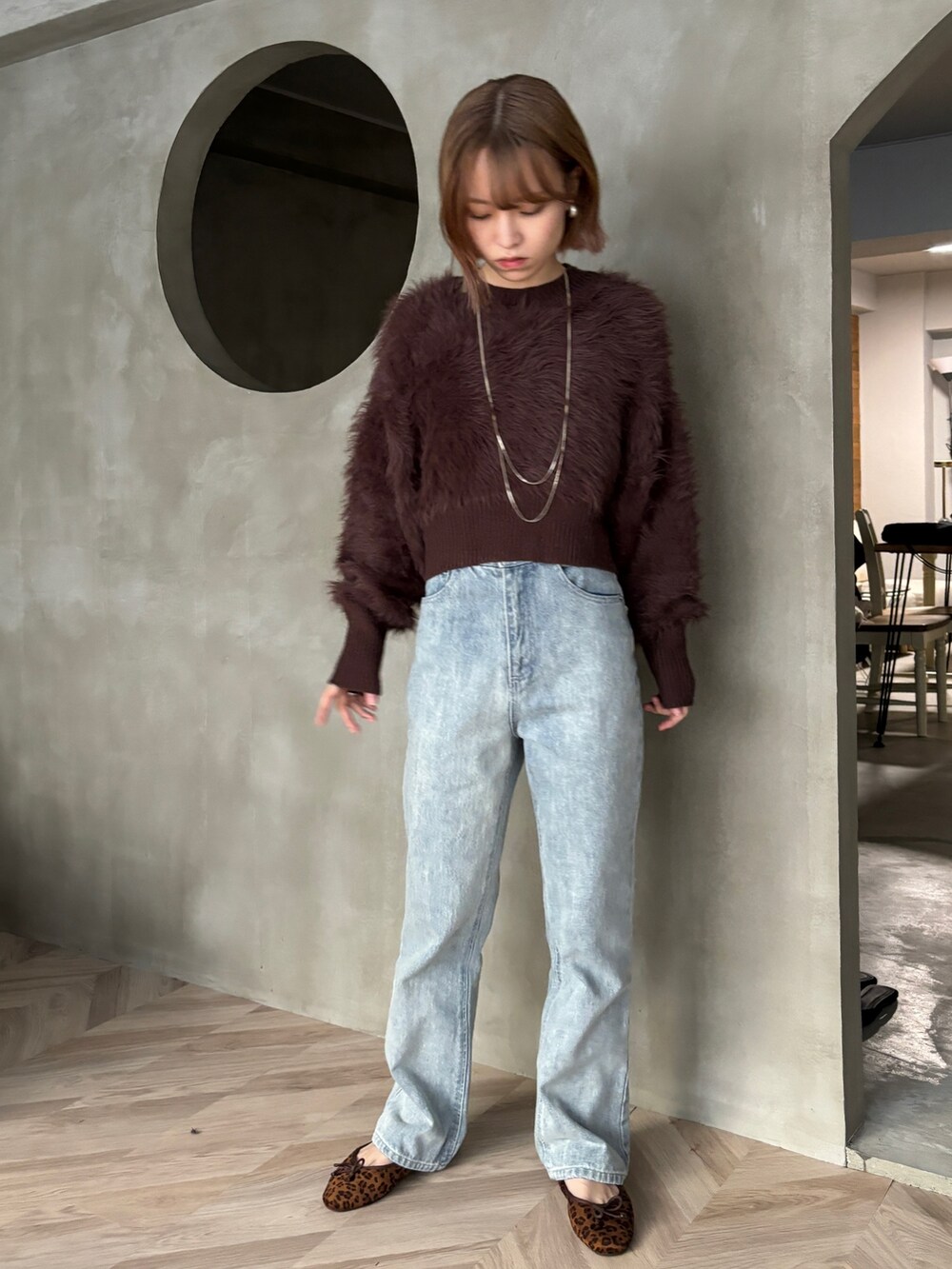 ブラック系のデニムパンツ、ブラウン系のバレエシューズ、ブラウン系のニット/セーターを着用したレディースの冬コーディネートの3枚目の写真