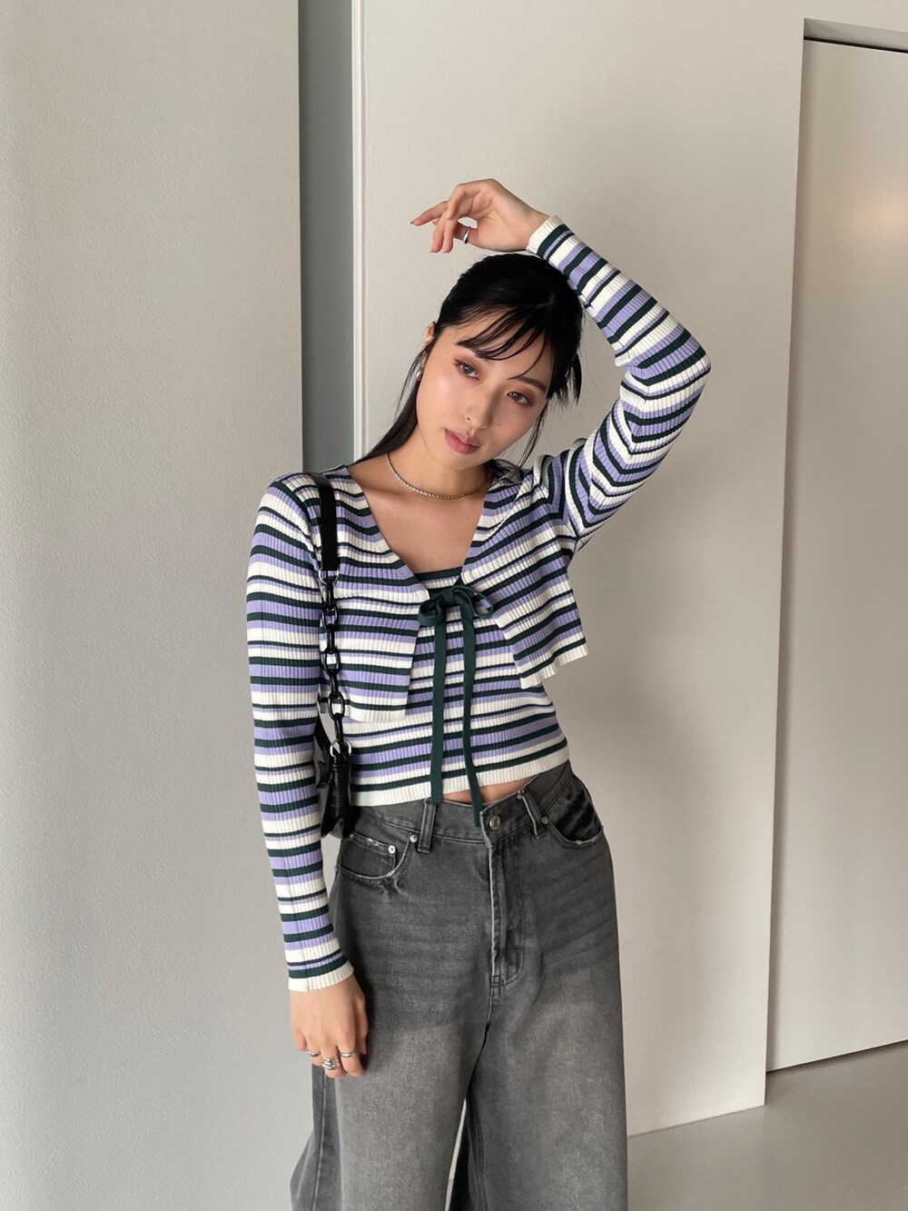 グレー系のトレンチコート、パープル系のカーディガン/ボレロ、パープル系のキャミソールを着用したレディースの春コーディネートの2枚目の写真