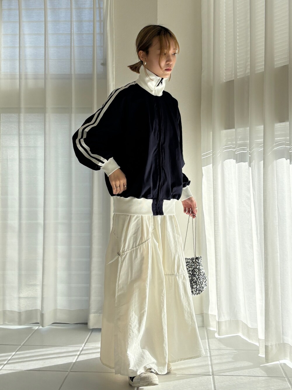 ブルー系のその他アウター、ホワイト系のスカート、ホワイト系のスニーカーを着用したレディースの冬コーディネートの2枚目の写真