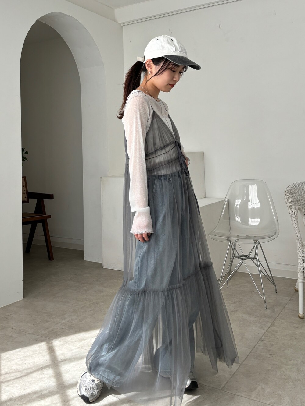 グレー系のワンピース、ホワイト系のTシャツ/カットソー、ブルー系のデニムパンツを着用したレディースの春コーディネートの2枚目の写真