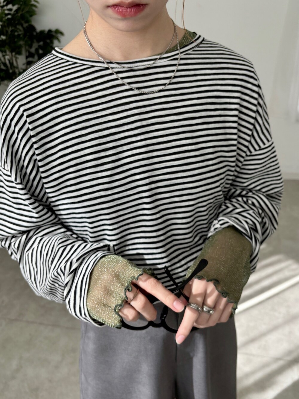 グレー系のスラックス、ホワイト系のTシャツ/カットソー、グリーン系のTシャツ/カットソーを着用したレディースの春コーディネートの3枚目の写真