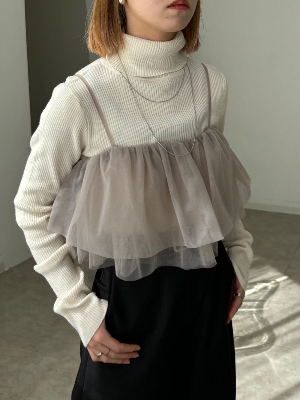 ブラック系のスラックス、ベージュ系のキャミソール、ホワイト系のニット/セーターを着用したレディースの春コーディネートの3枚目の写真