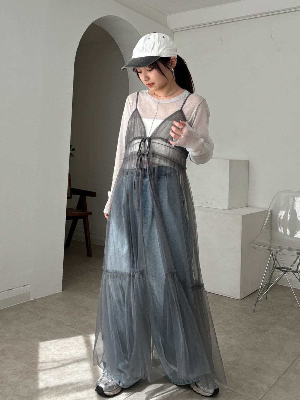 グレー系のワンピース、ホワイト系のTシャツ/カットソー、ブルー系のデニムパンツを着用したレディースの春コーディネートの5枚目の写真