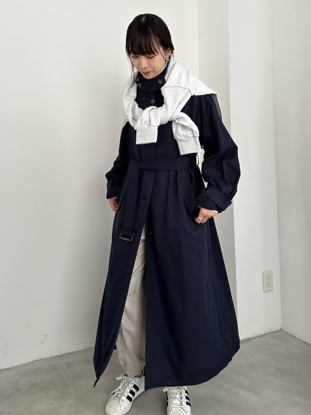 ブルー系のステンカラーコート、ホワイト系のカーゴパンツ、ホワイト系のスニーカーを着用したレディースの冬コーディネートの2枚目の写真