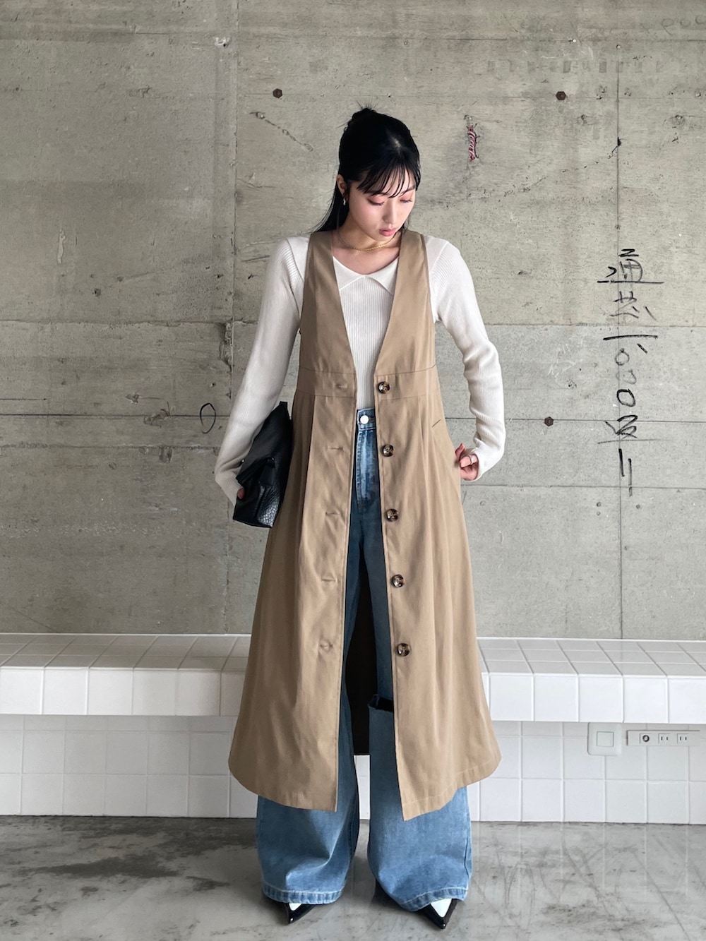 ブルー系のデニムパンツ、ベージュ系のトレンチコート、ホワイト系のニット/セーターを着用したレディースの冬コーディネートの2枚目の写真