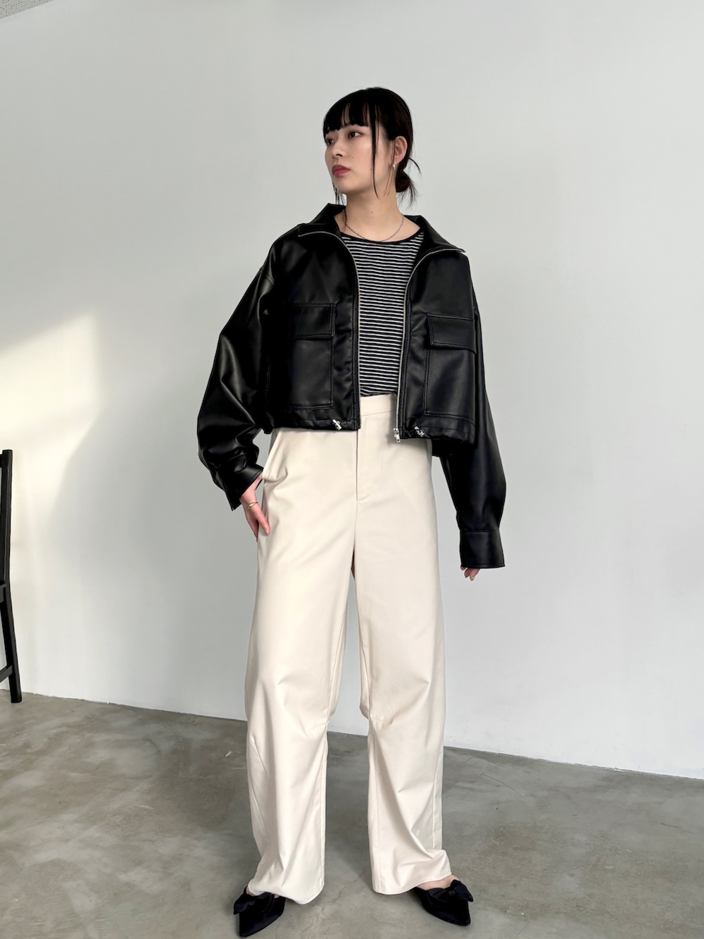 ホワイト系のスラックス、ブラック系のタンクトップ、ブラック系のブルゾンを着用したレディースの冬コーディネートの3枚目の写真