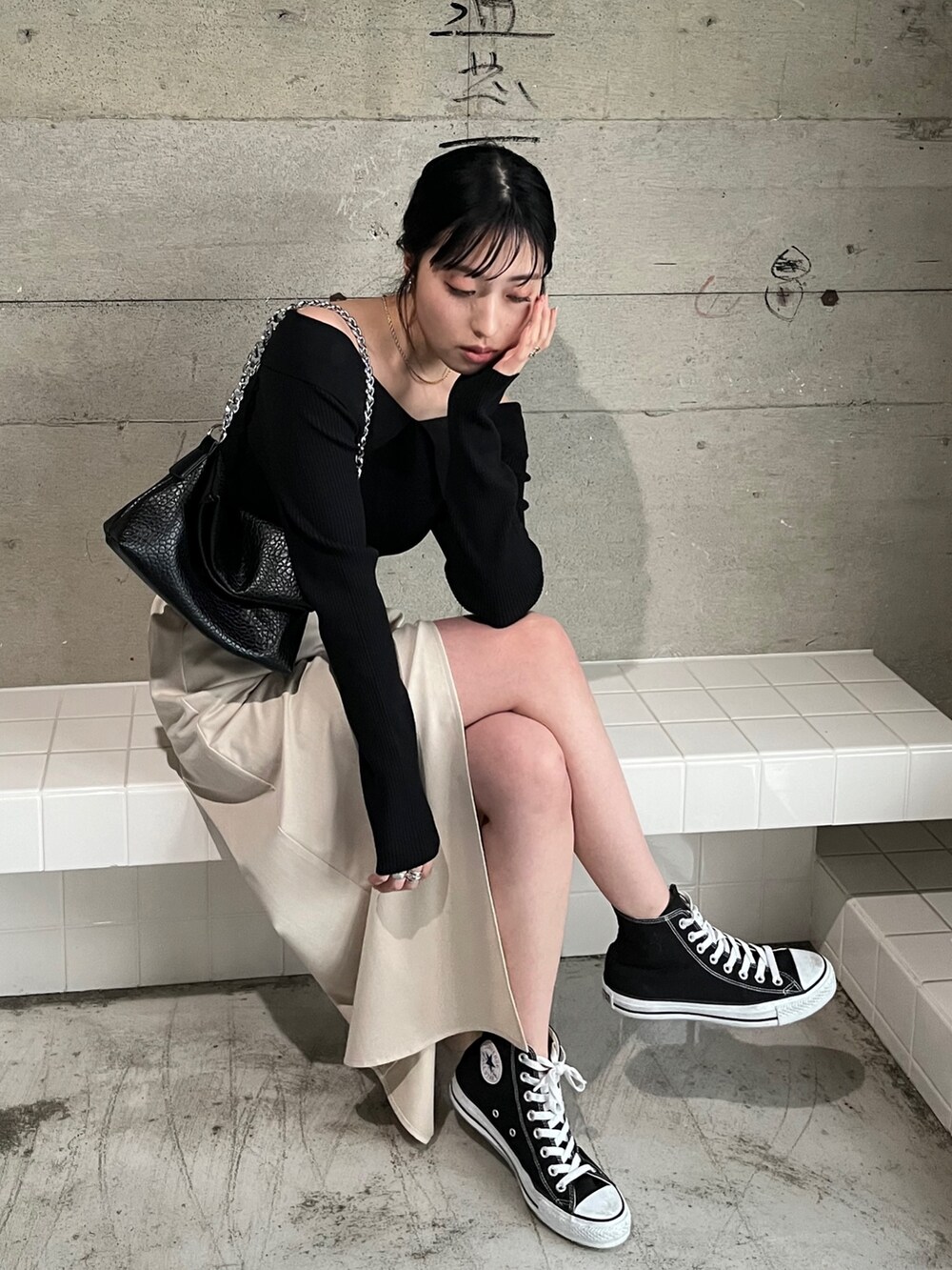 ホワイト系のスカート、ブラック系のスニーカー、ブラック系のニット/セーターを着用したレディースの春コーディネートの3枚目の写真