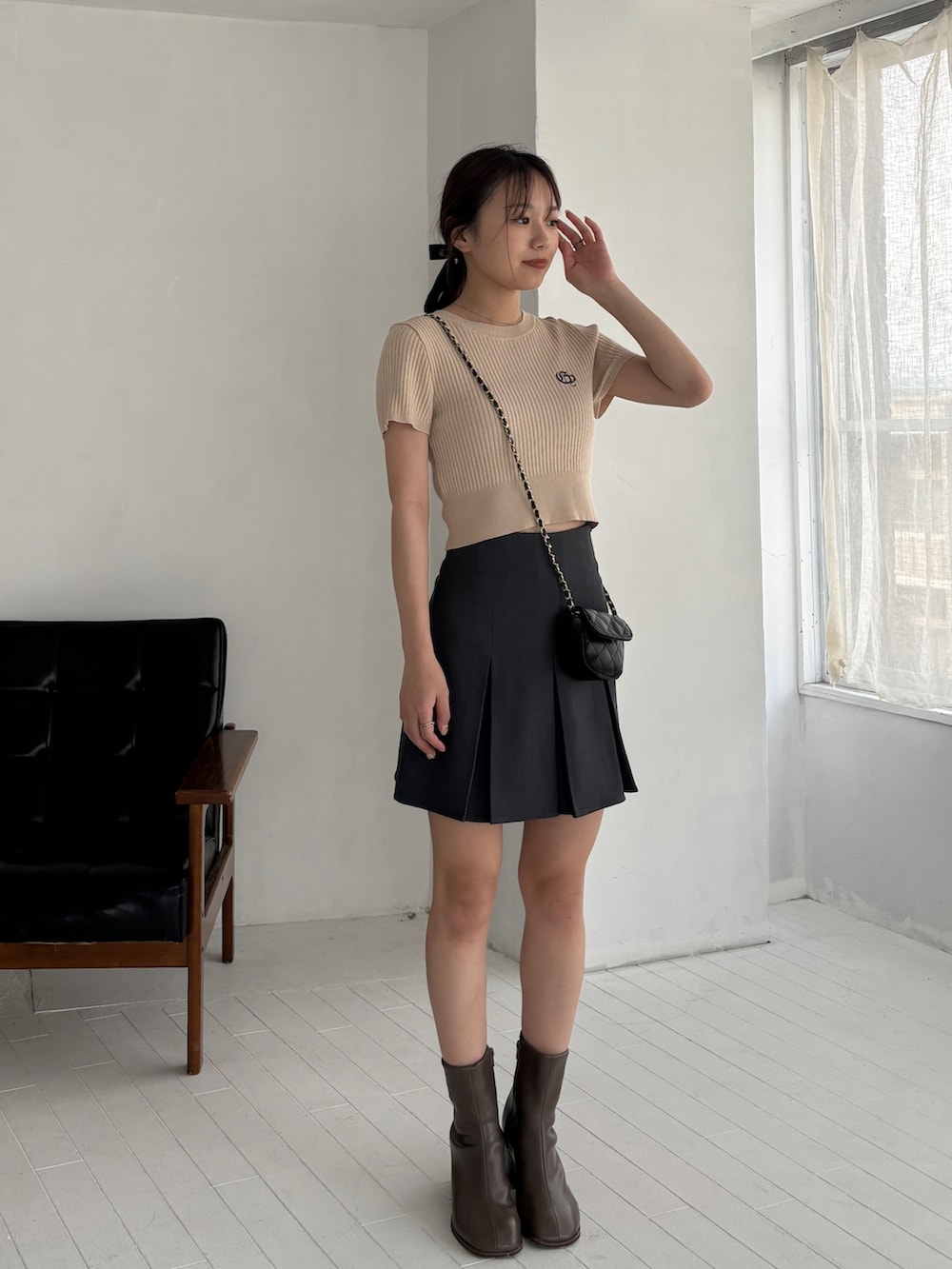 グレー系のスカート、ベージュ系のニット/セーター、ブラウン系のブーツを着用したレディースの秋コーディネートの2枚目の写真