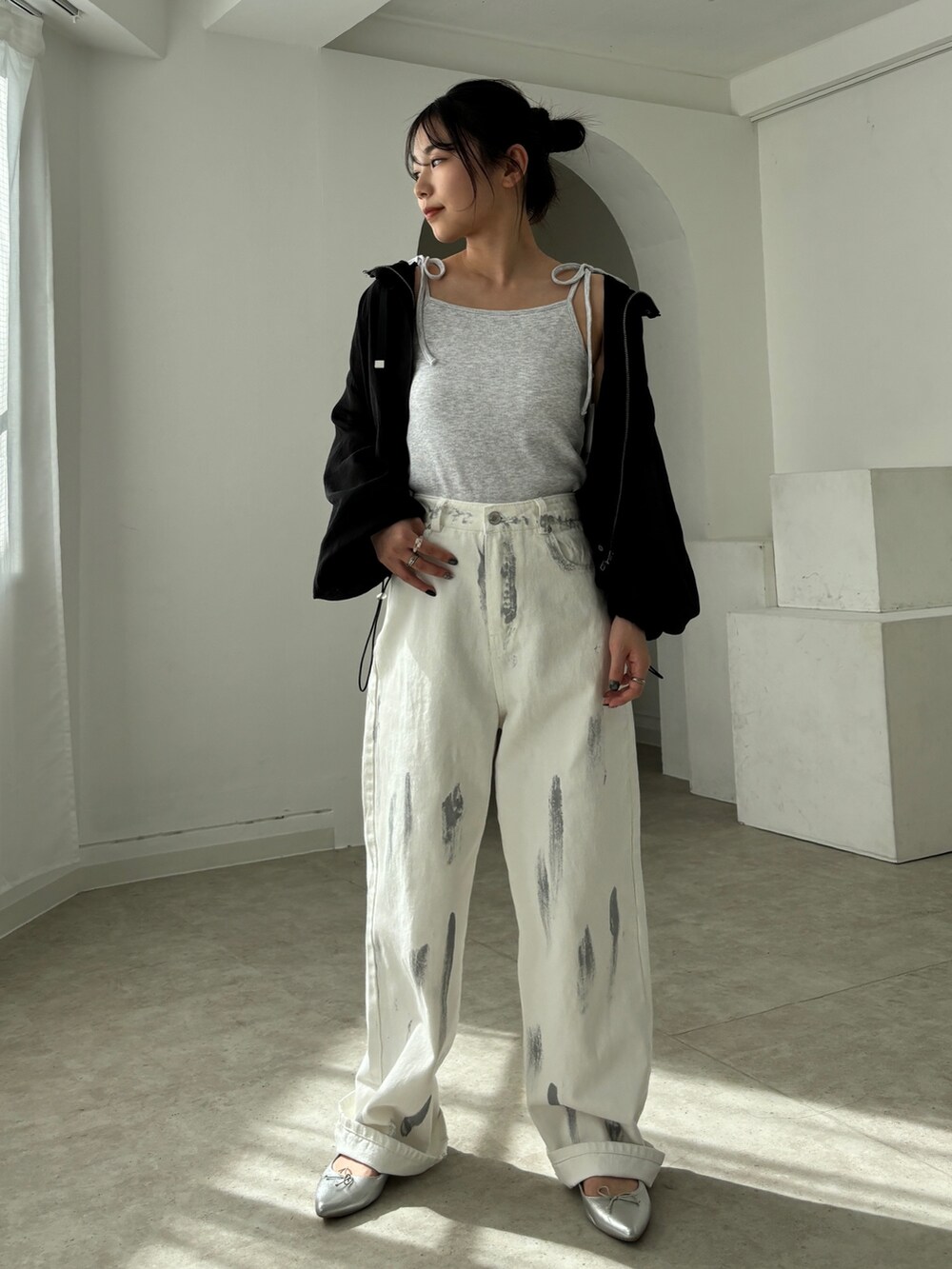 ホワイト系のデニムパンツ、ブラック系のマウンテンパーカー、ベージュ系のキャミソールを着用したレディースの春コーディネートの3枚目の写真