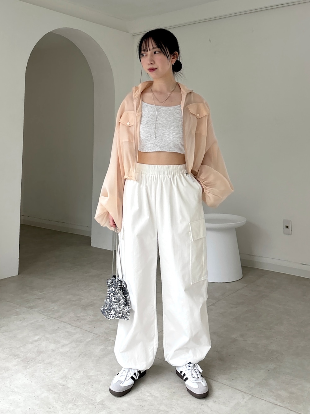 ホワイト系のカーゴパンツ、ホワイト系のスニーカー、ベージュ系のタンクトップを着用したレディースの春コーディネートの3枚目の写真