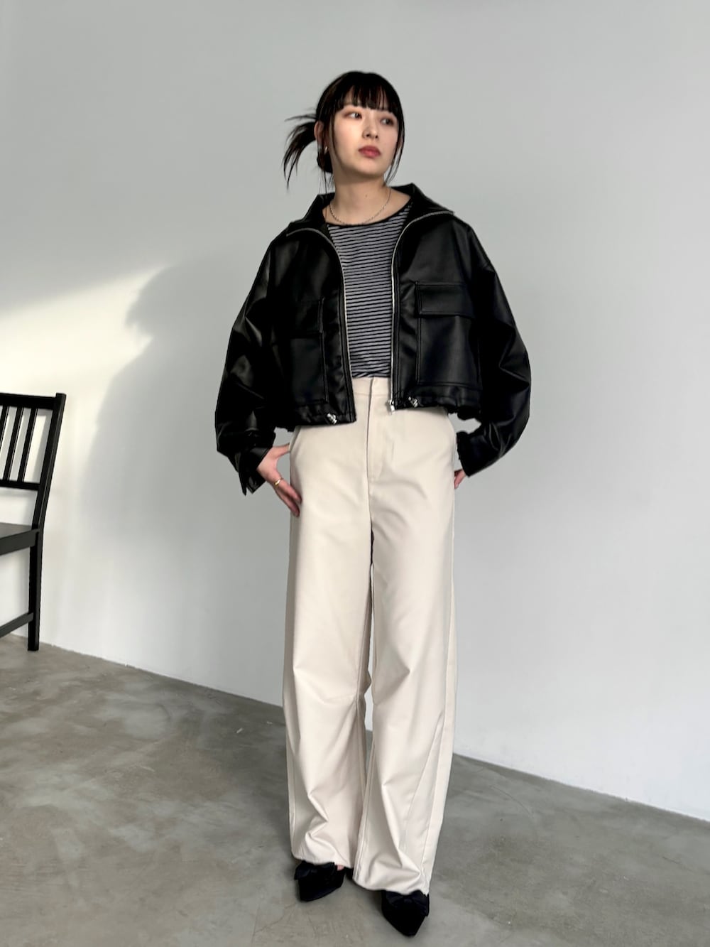 ホワイト系のスラックス、ブラック系のタンクトップ、ブラック系のブルゾンを着用したレディースの冬コーディネートの2枚目の写真
