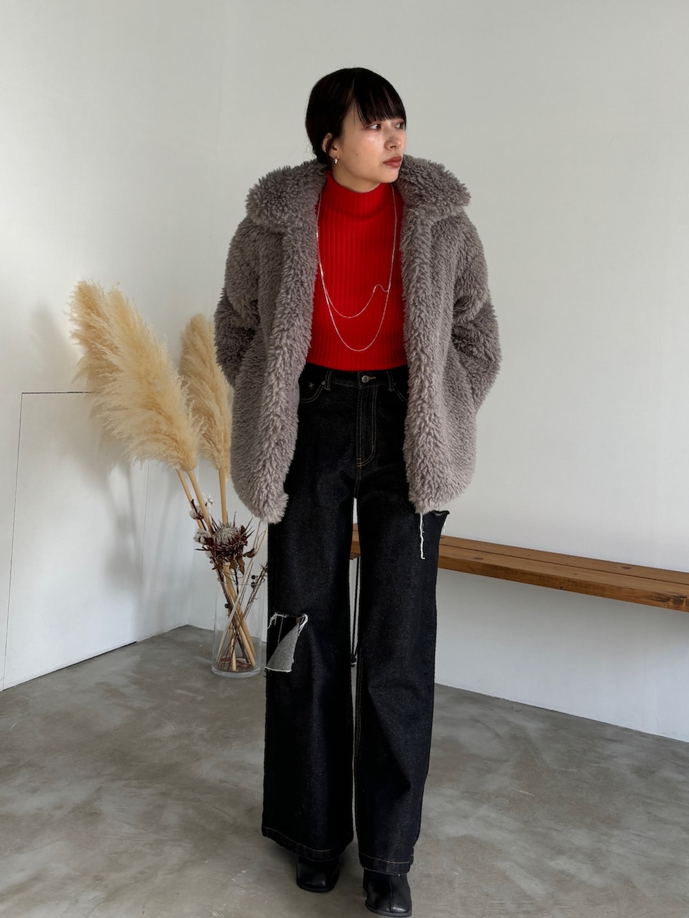 ブラック系のデニムパンツ、ブラック系のブーツ、レッド系のニット/セーターを着用したレディースの冬コーディネートの3枚目の写真
