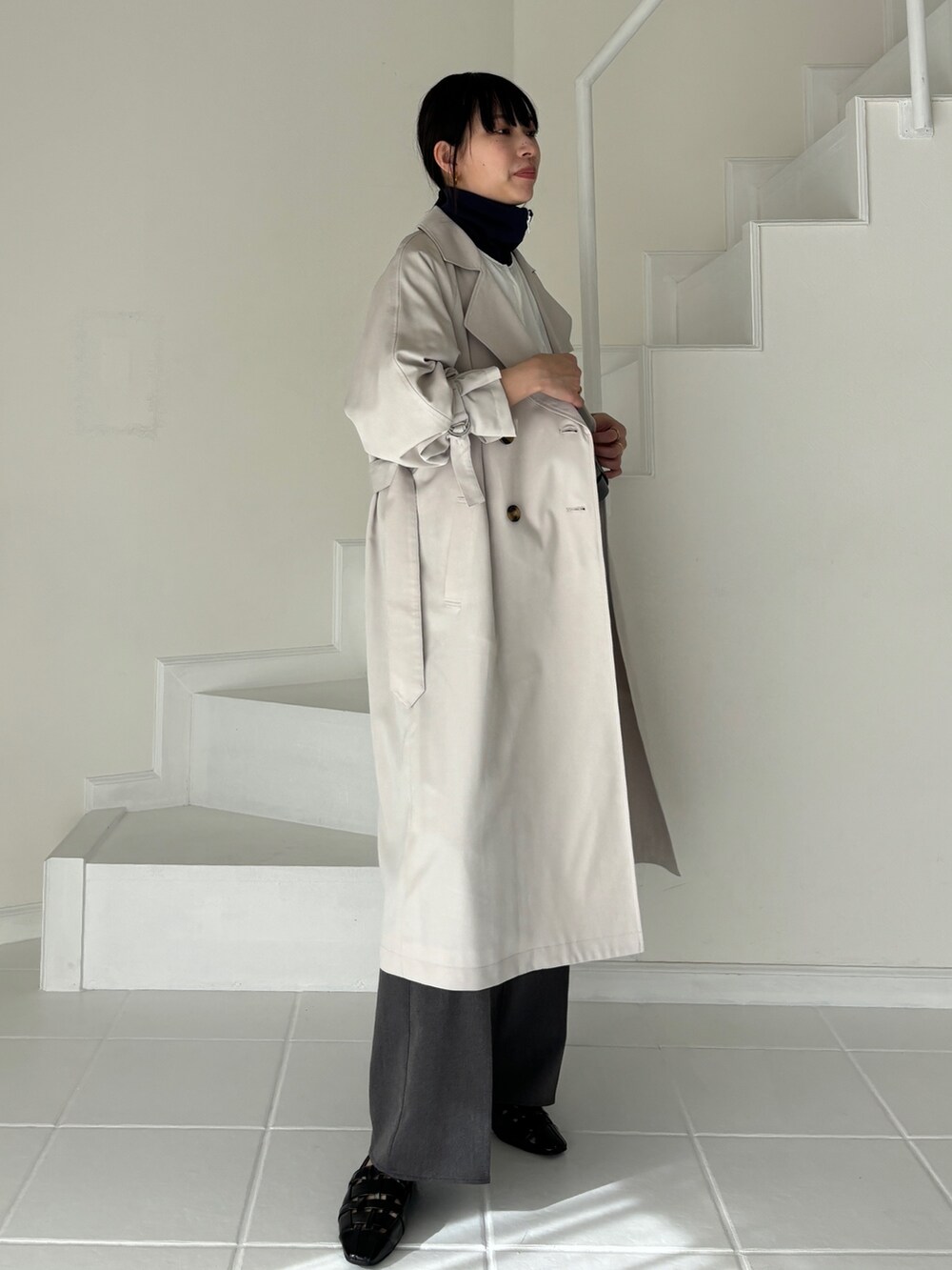 グレー系のトレンチコート、ホワイト系のその他アウター、グレー系のスラックスを着用したレディースの冬コーディネートの3枚目の写真