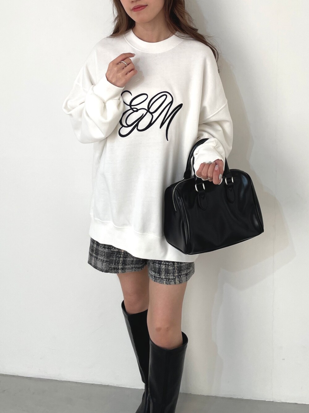 ブラック系のスウェット、ホワイト系のニット/セーター、オレンジ系のハンドバッグを着用したレディースの冬コーディネートの3枚目の写真