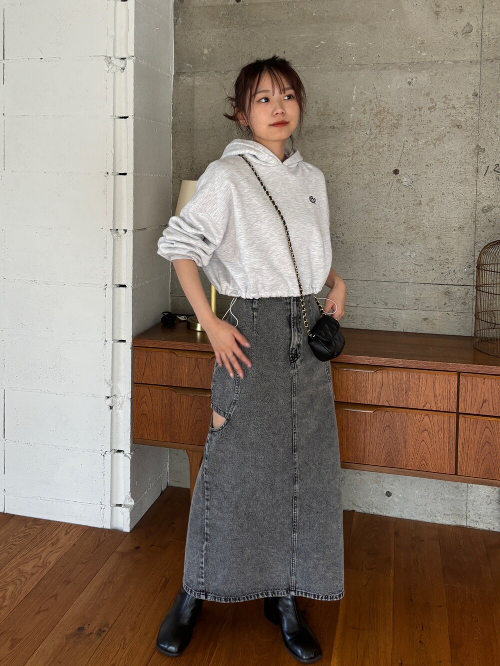 ベージュ系のパーカー、ブラック系のデニムスカート、ブラック系のブーツを着用したレディースの秋コーディネートの2枚目の写真