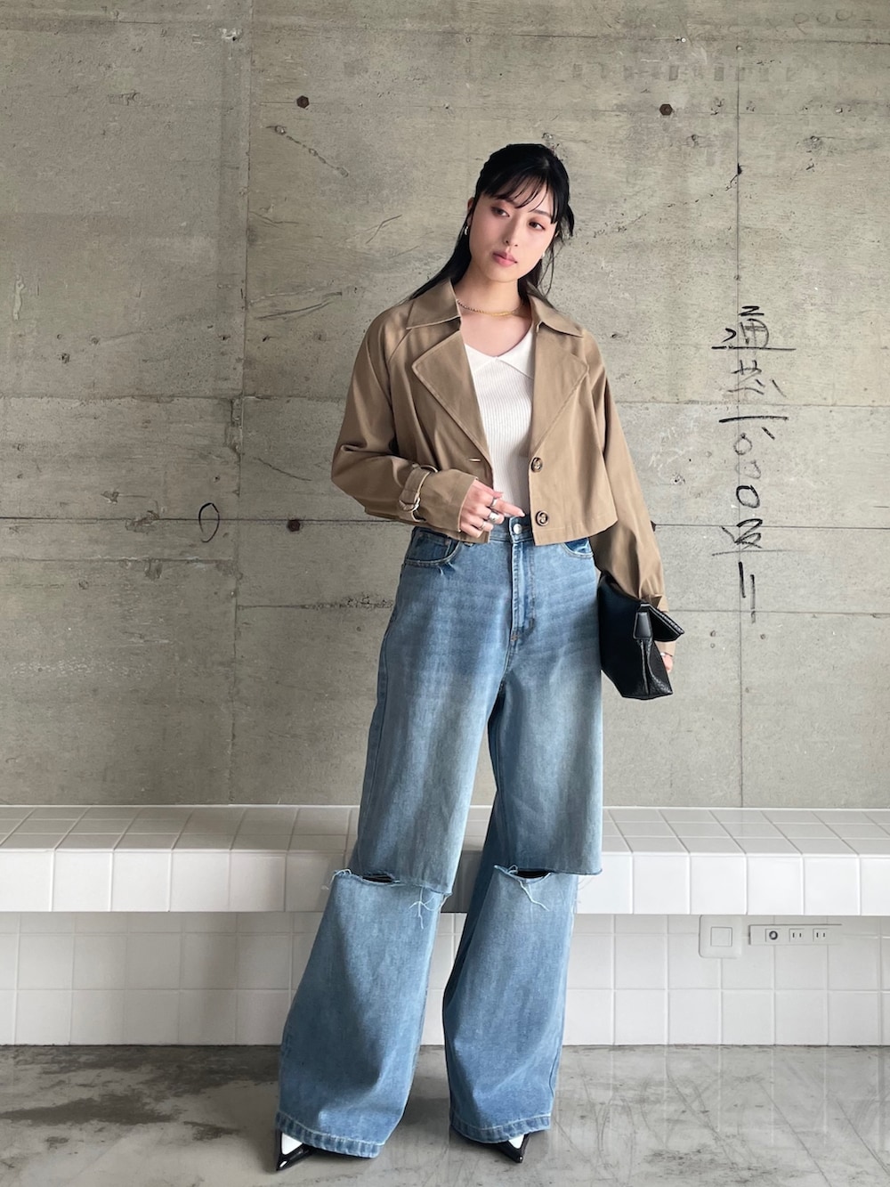 ブルー系のデニムパンツ、ベージュ系のトレンチコート、ホワイト系のニット/セーターを着用したレディースの冬コーディネートの3枚目の写真