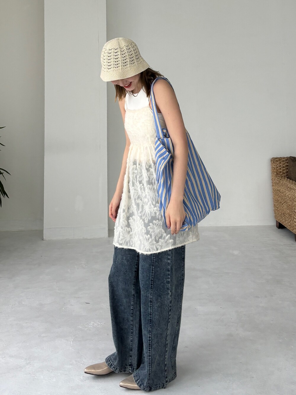 ブルー系のトートバッグ、ホワイト系のチュニック、ブルー系のデニムパンツを着用したレディースの夏コーディネートの2枚目の写真