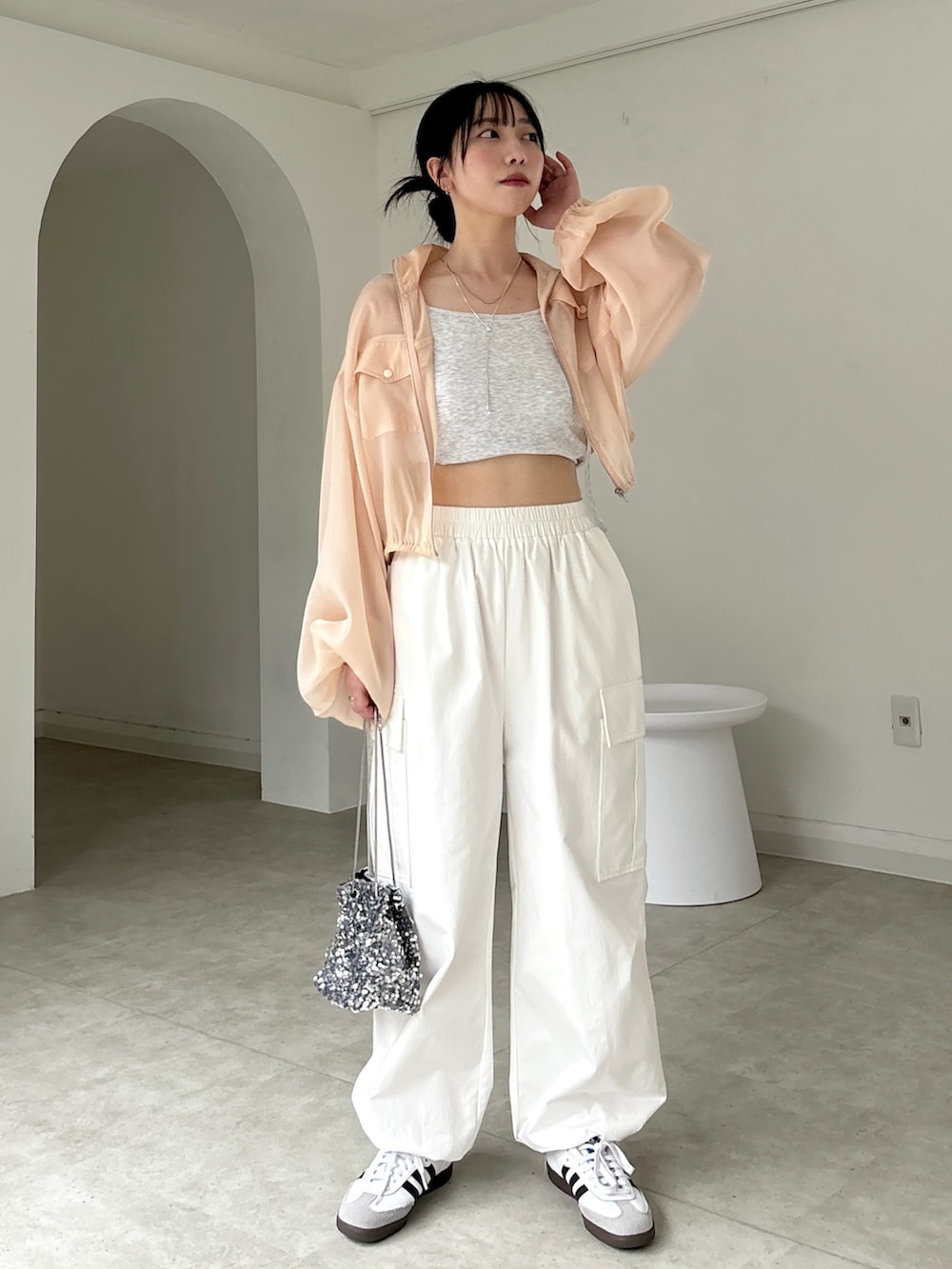 ホワイト系のカーゴパンツ、ホワイト系のスニーカー、ベージュ系のタンクトップを着用したレディースの春コーディネートの2枚目の写真