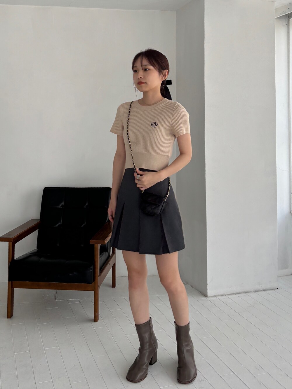 グレー系のスカート、ベージュ系のニット/セーター、ブラウン系のブーツを着用したレディースの秋コーディネートの3枚目の写真