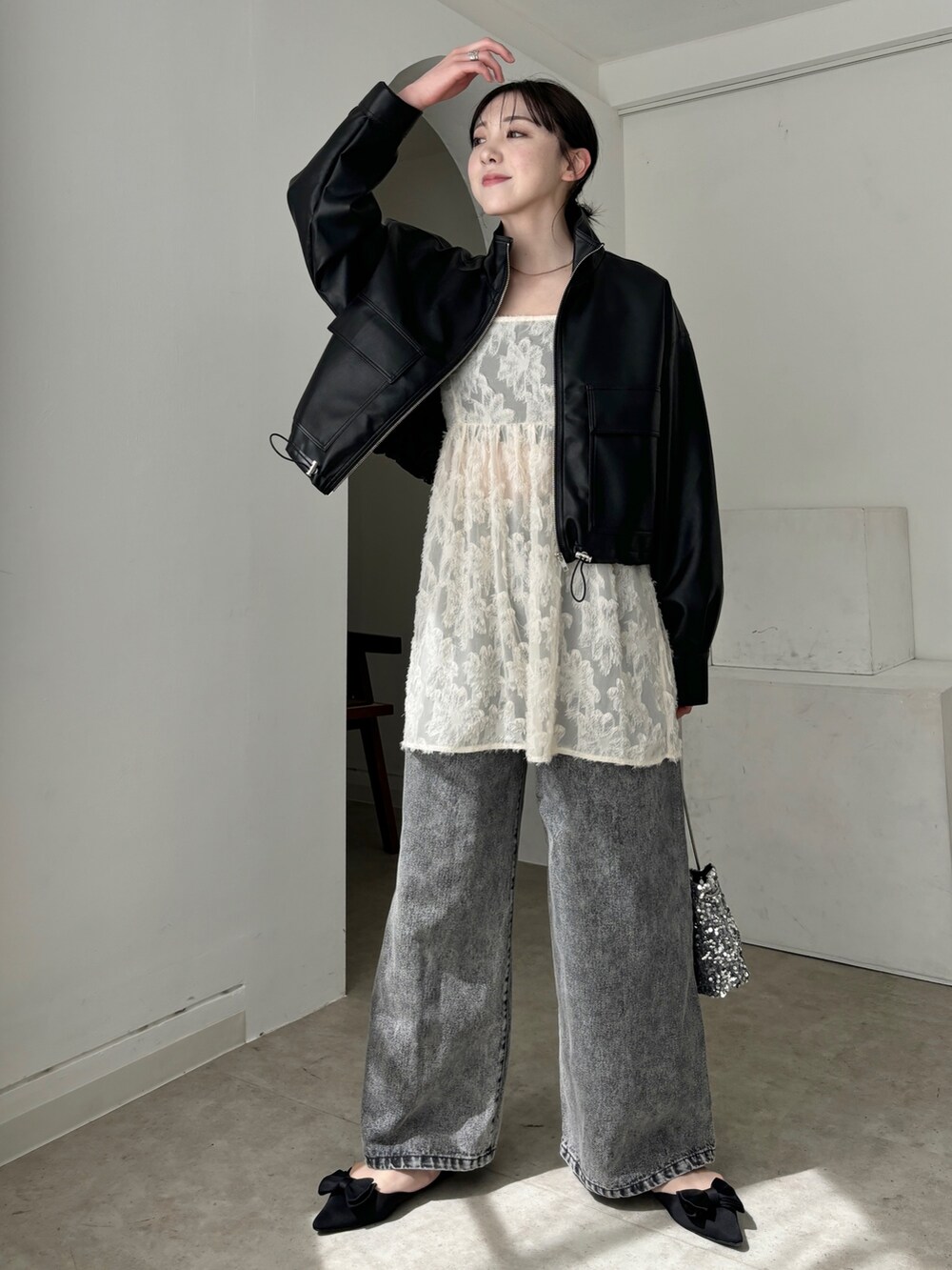 ホワイト系のチュニック、ブラック系のブルゾン、グレー系のデニムパンツを着用したレディースの春コーディネートの2枚目の写真