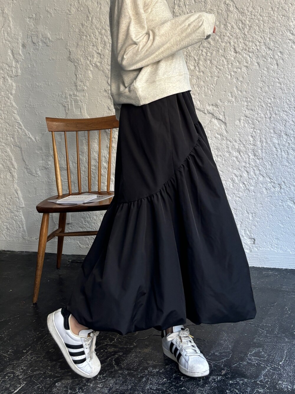 ブラック系のスカート、ホワイト系のスニーカー、ベージュ系のポロシャツを着用したレディースの冬コーディネートの7枚目の写真