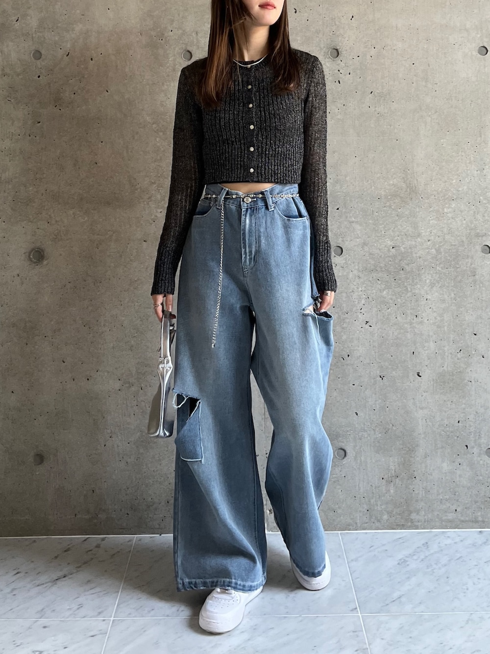 ブルー系のデニムパンツ、ブラック系のカーディガン/ボレロ、ホワイト系のスニーカーを着用したレディースの春コーディネートの2枚目の写真