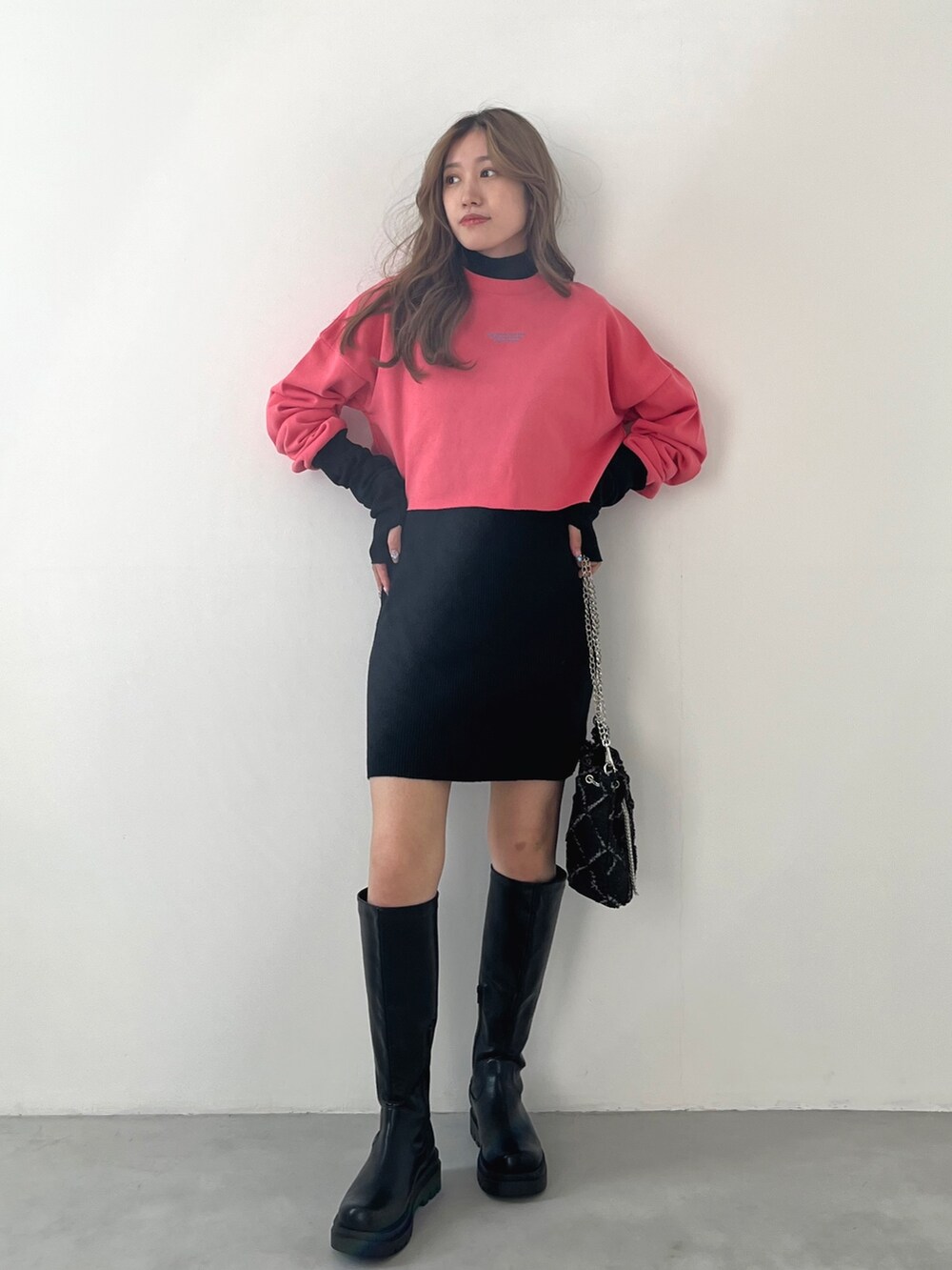 ブラック系のワンピース、ピンク系のスウェット、ブラック系のブーツを着用したレディースの秋コーディネートの2枚目の写真