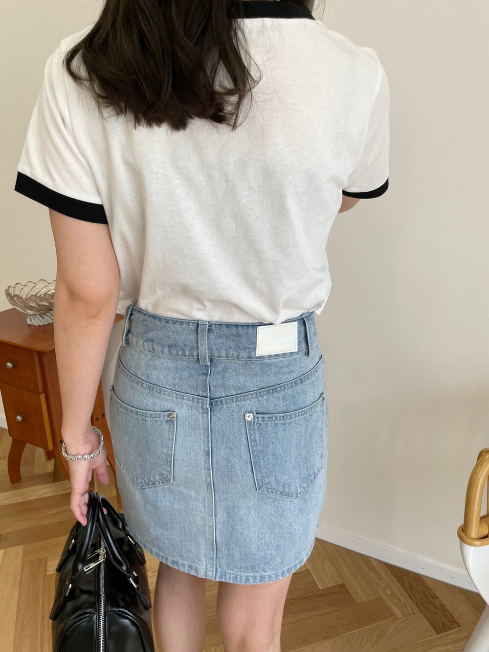 ブラック系のボストンバッグ、ブルー系のデニムスカート、ブラック系のスニーカーを着用したレディースの夏コーディネートの2枚目の写真