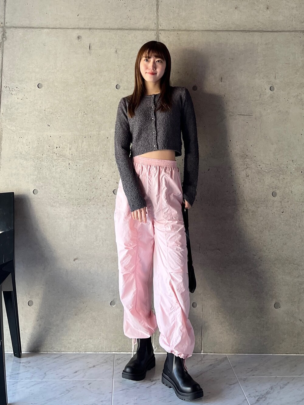 グレー系のカーディガン/ボレロ、ピンク系のカーゴパンツ、ブラック系のブーツを着用したレディースの春コーディネートの2枚目の写真