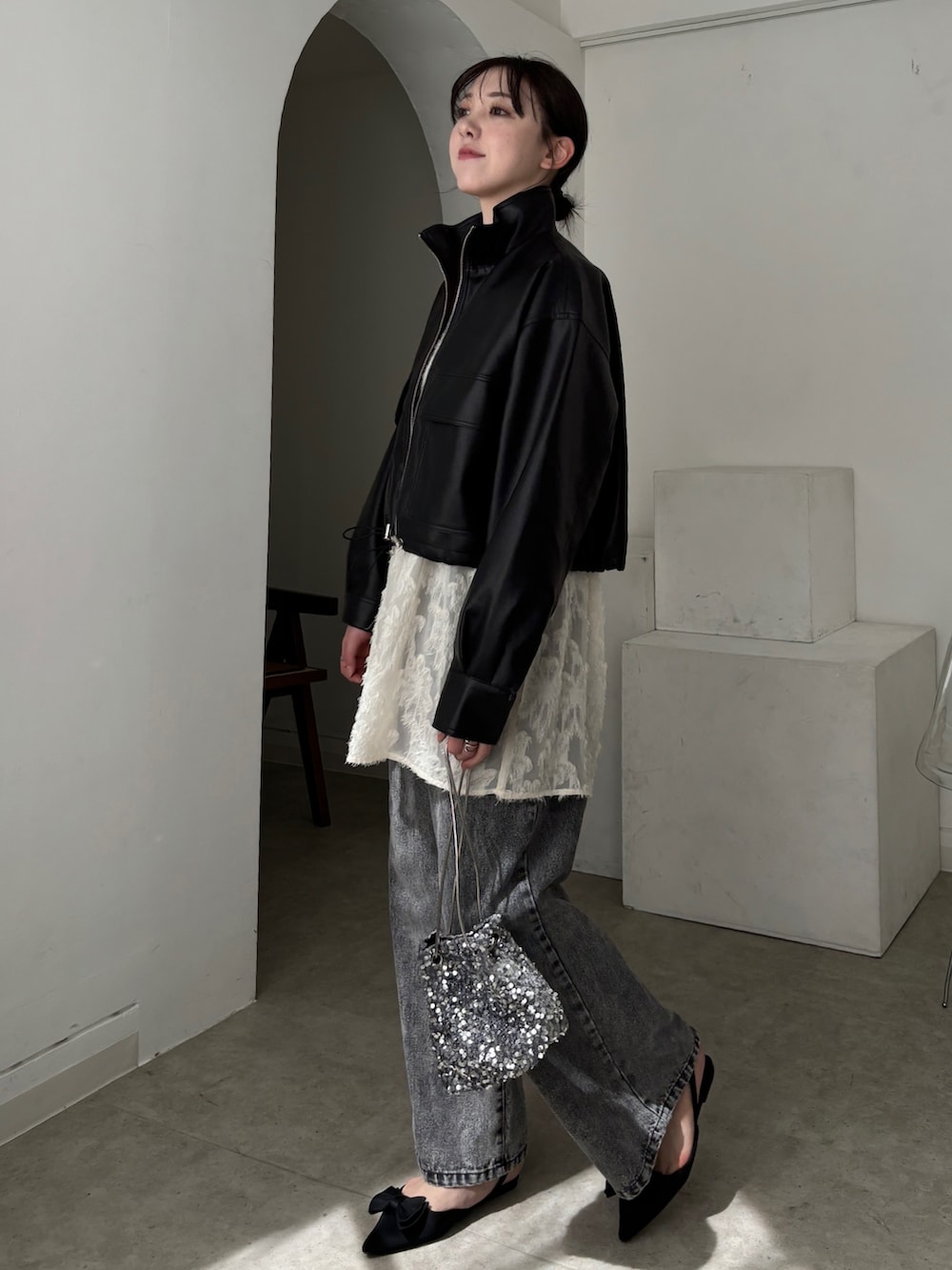 ホワイト系のチュニック、ブラック系のブルゾン、グレー系のデニムパンツを着用したレディースの春コーディネートの3枚目の写真