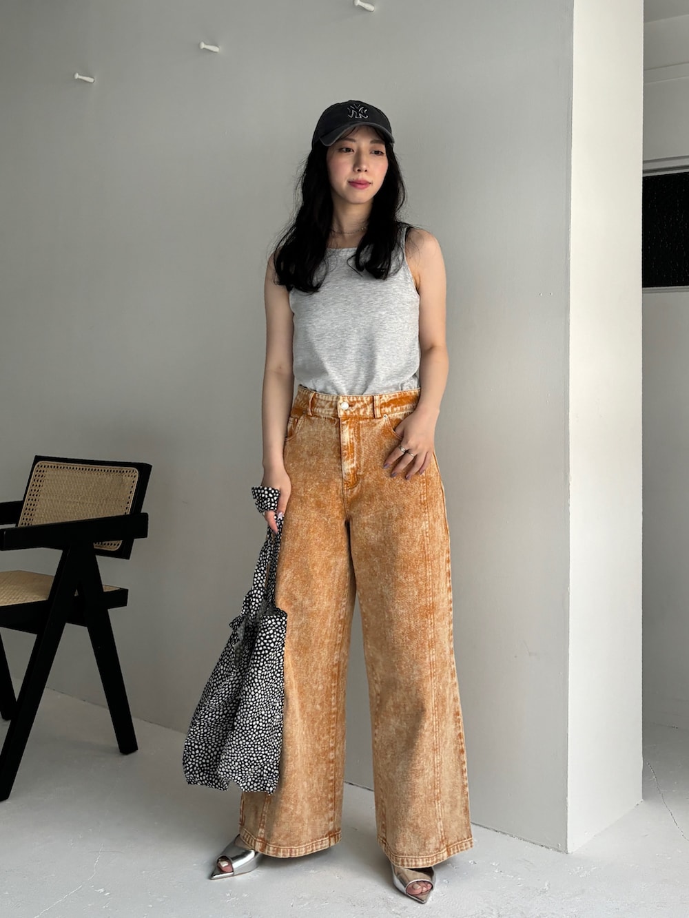 オレンジ系のデニムパンツ、ベージュ系のタンクトップ、シルバー系のサンダルを着用したレディースの夏コーディネートの2枚目の写真