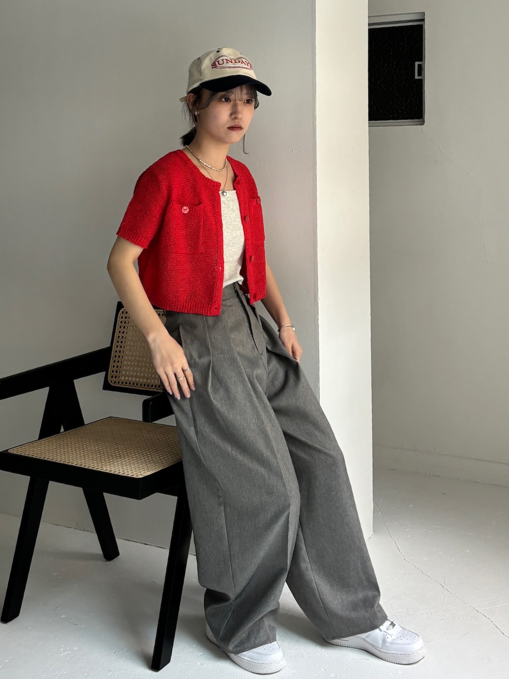 グレー系のスラックス、レッド系のカーディガン/ボレロ、ベージュ系のキャミソールを着用したレディースの夏コーディネートの3枚目の写真