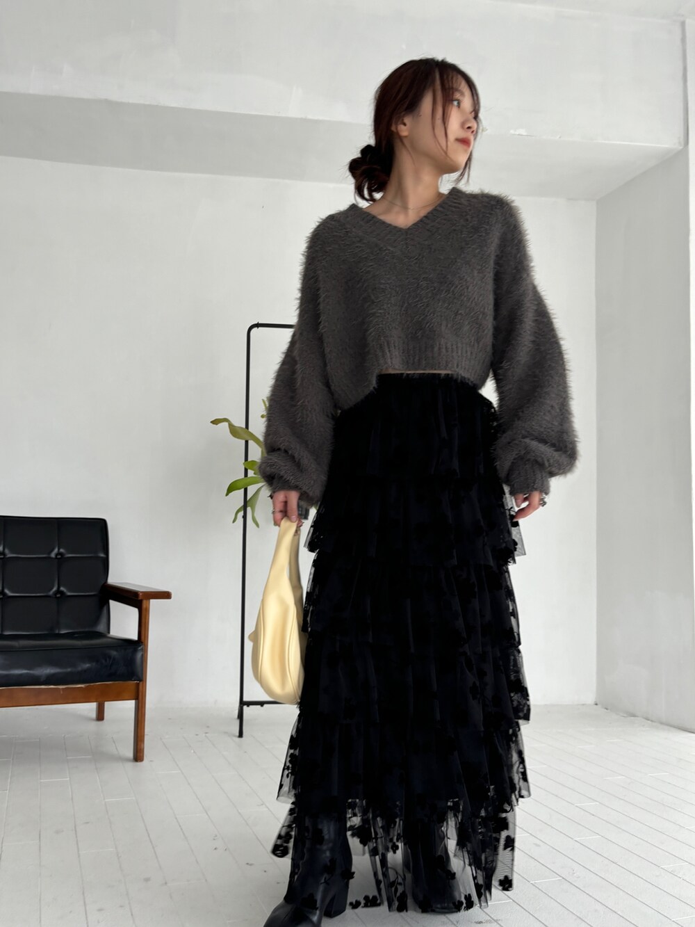 グレー系のニット/セーター、ブラック系のスカート、ブラック系のブーツを着用したレディースの秋コーディネートの4枚目の写真