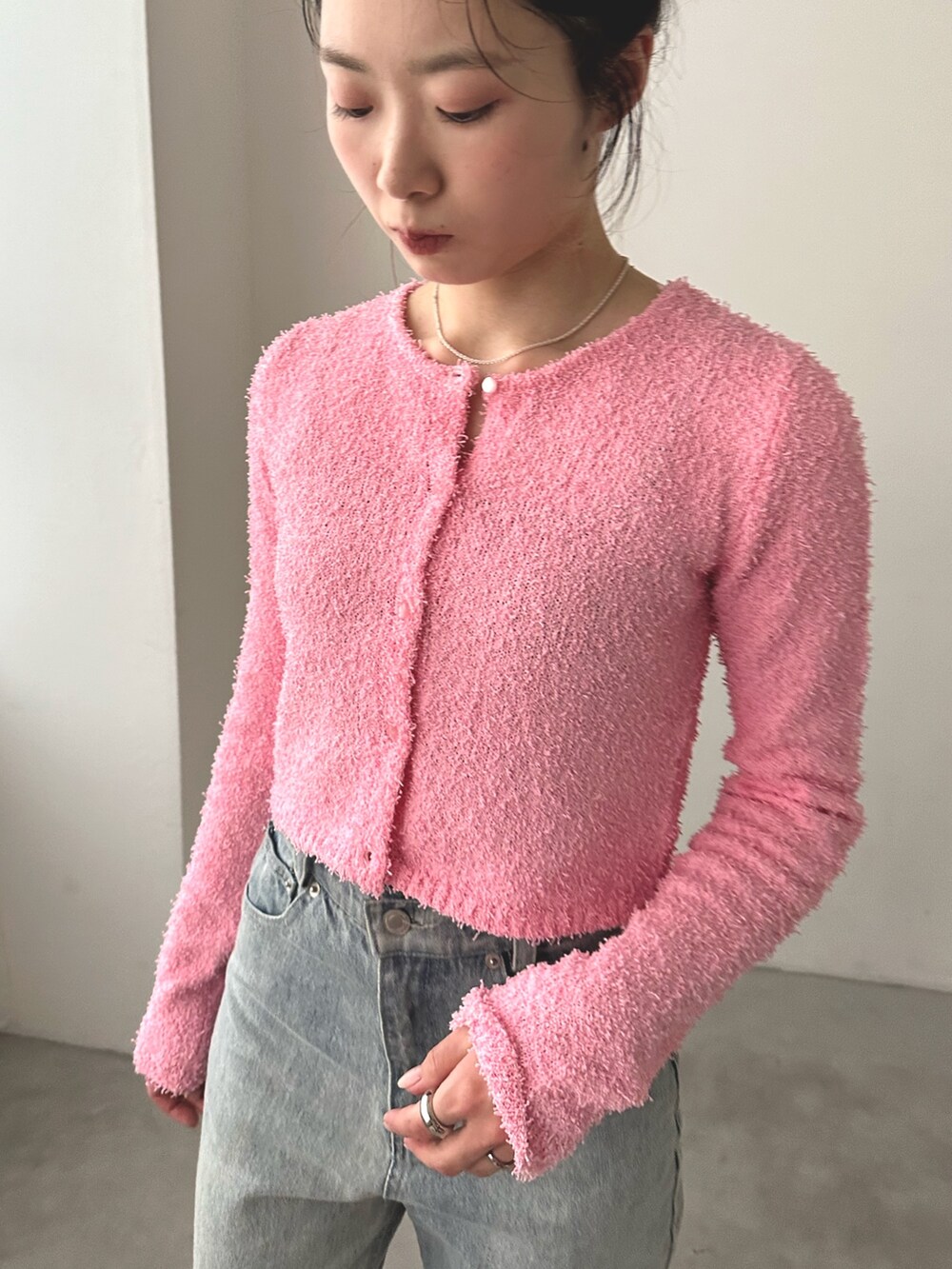 ブルー系のデニムパンツ、シルバー系のバレエシューズ、ピンク系のカーディガン/ボレロを着用したレディースの秋コーディネートの3枚目の写真