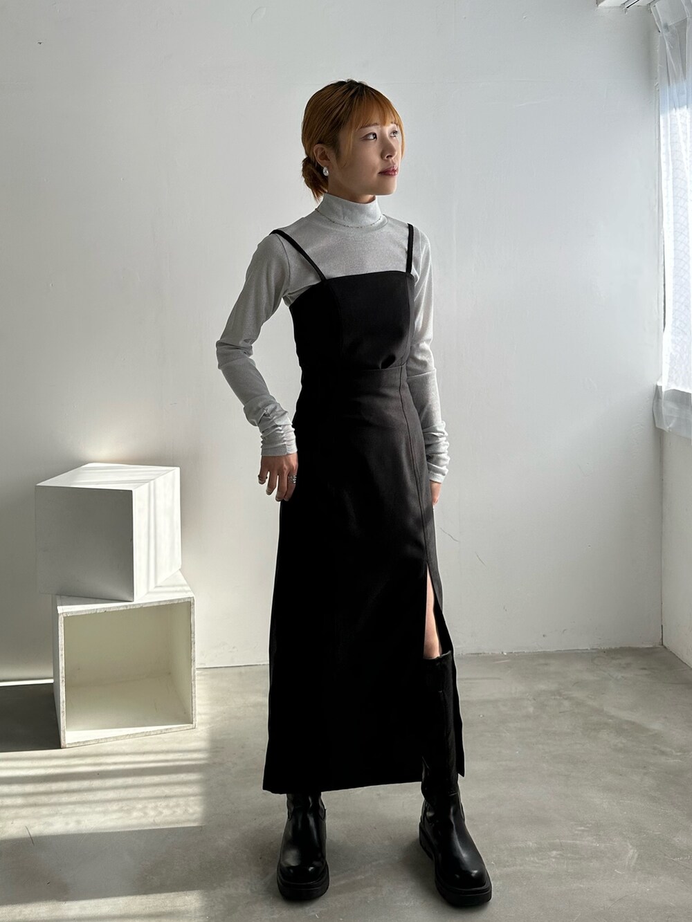 ブラック系のワンピース、ホワイト系のTシャツ/カットソー、ブラック系のブーツを着用したレディースの冬コーディネートの2枚目の写真