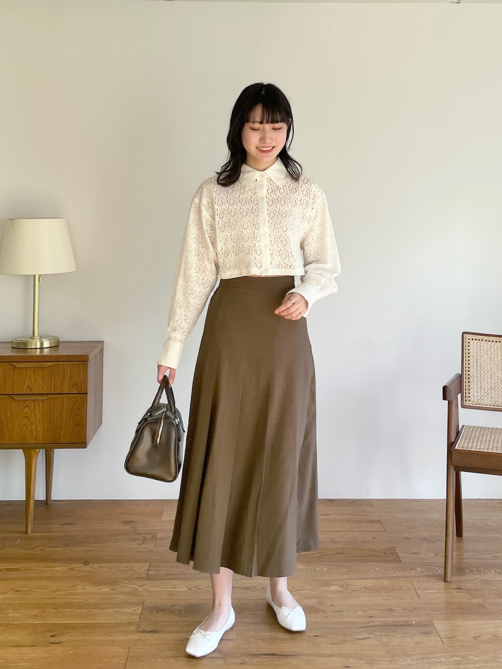 ブラウン系のスカート、ベージュ系のTシャツ/カットソー、ブラック系のスニーカーを着用したレディースの春コーディネートの2枚目の写真