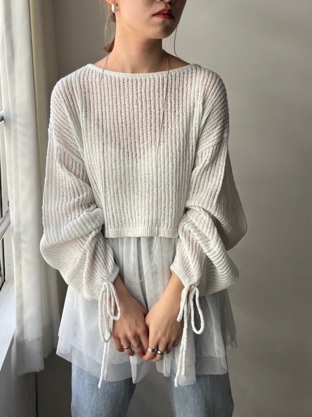 ホワイト系のシャツ/ブラウス、ホワイト系のニット/セーター、ブルー系のデニムパンツを着用したレディースの春コーディネートの6枚目の写真